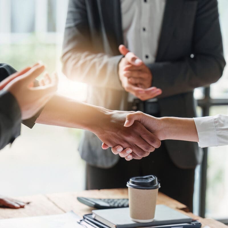 Business people shaking hands over table at meeting